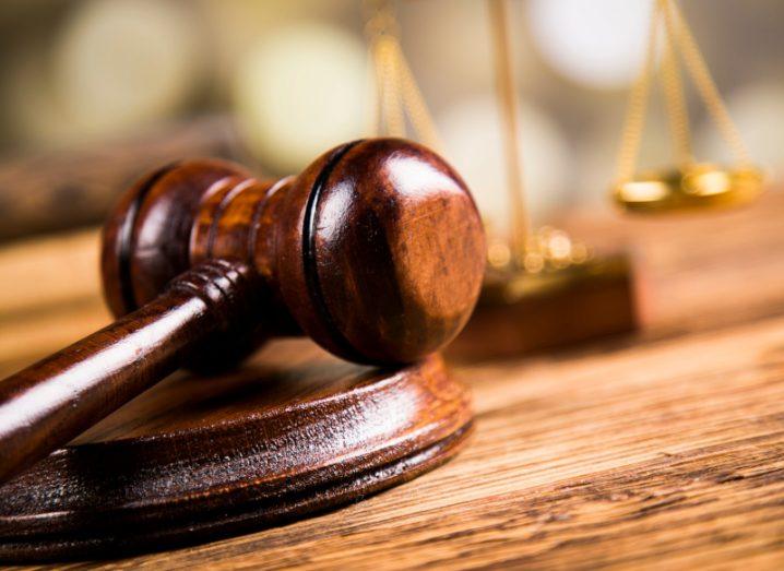 Close-up of a wooden gavel with scales representing justice in the background.