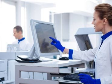 Life sciences workers in a lab looking at a computer.