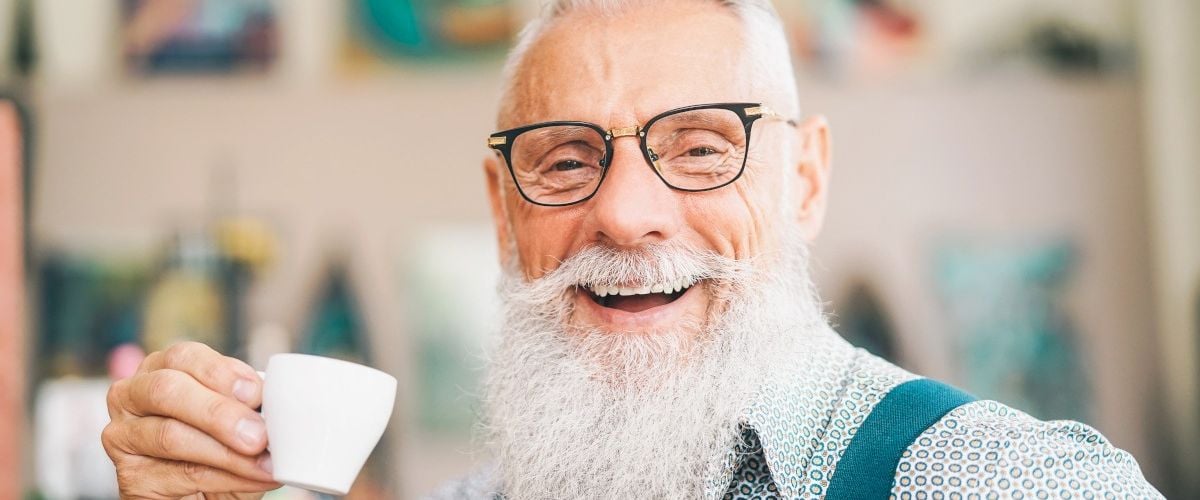 Older influencer and member of the creator economy sitting in a cafe drinking coffee.