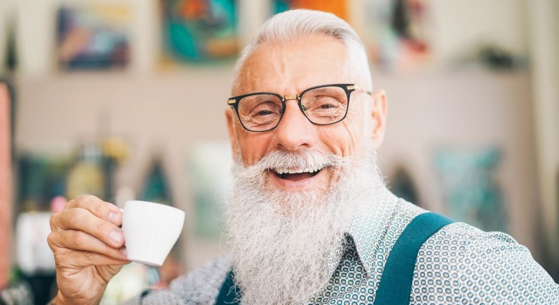 Older influencer and member of the creator economy sitting in a cafe drinking coffee.