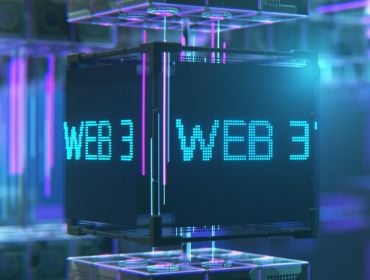 A cube with Web3 written on it in neon blue letters. The background is digitised in blue and purple lights.