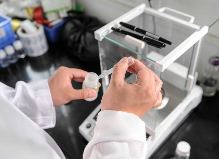 A scientist researcher mixing a solution in a lab with lab equipment in the background.