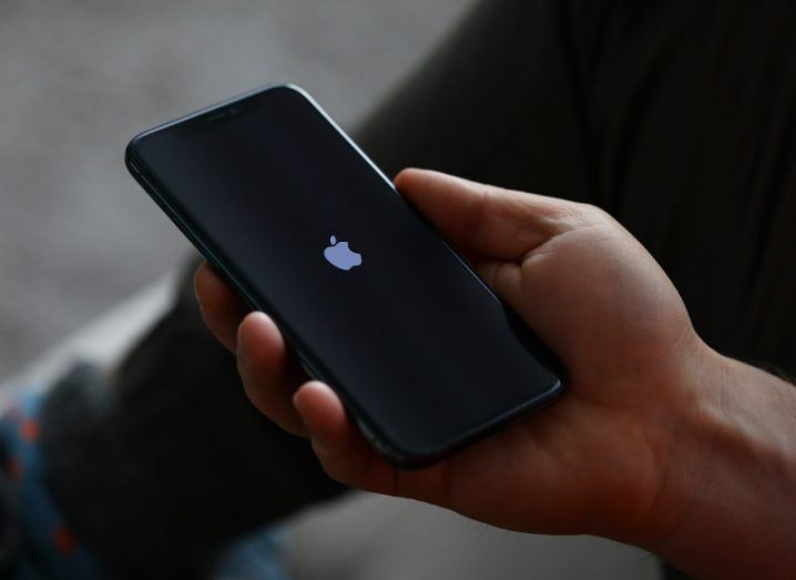 The Apple logo on the screen of an iPhone, which is in a person's hand.