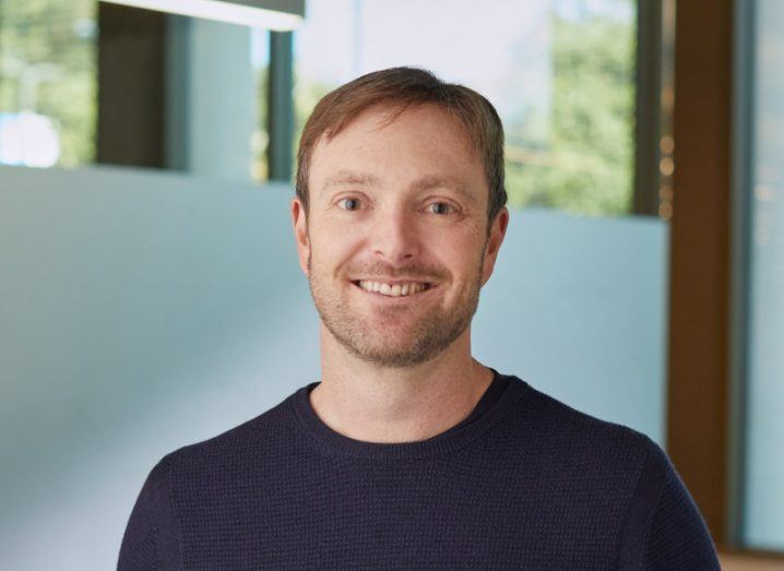 A man in a jumper, smiling with a window behind him. He is Alex Chriss of Intuit and the next CEO of PayPal.