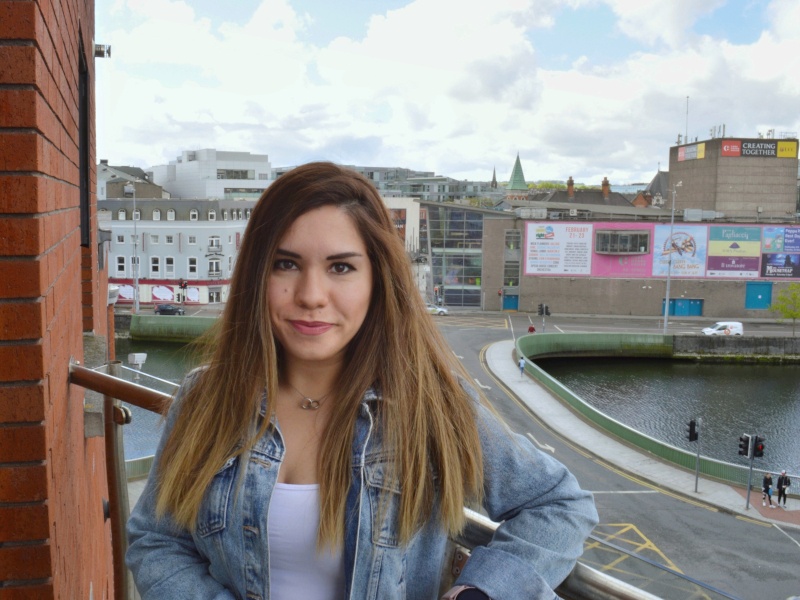 Begum Genc stands on a balcony overlooking a city street.