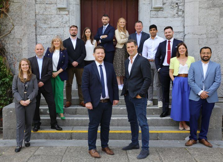 A group of men and women stand on the stairs at the Quadrangle in University of Galway.