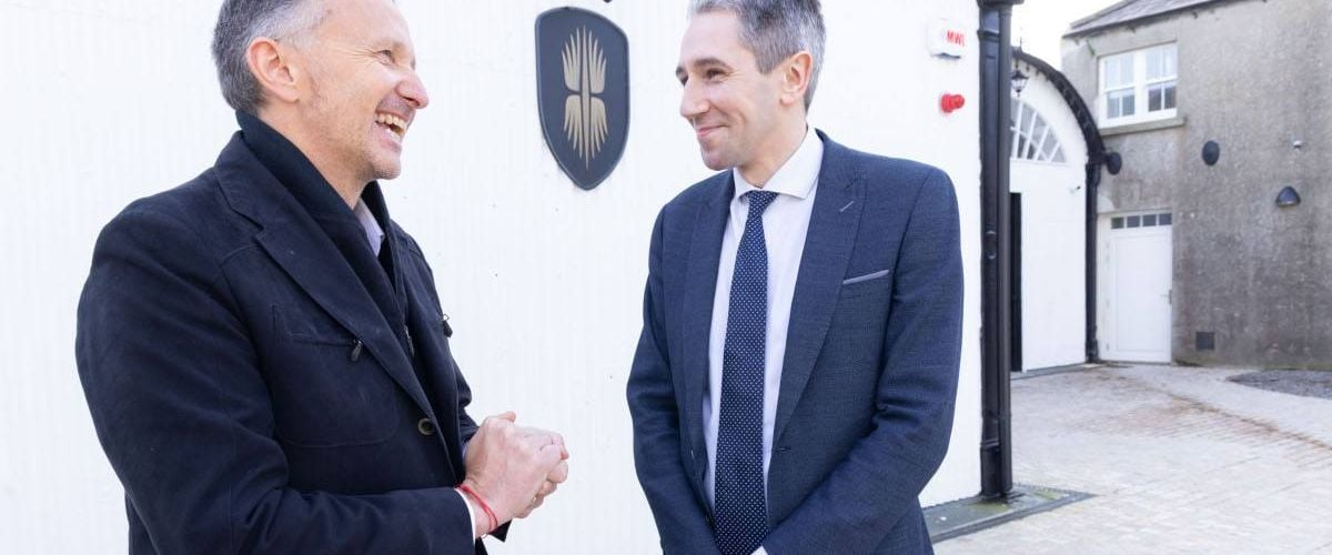 Two men standing outside a white building celebrating the announcement of jobs for Cool Planet.