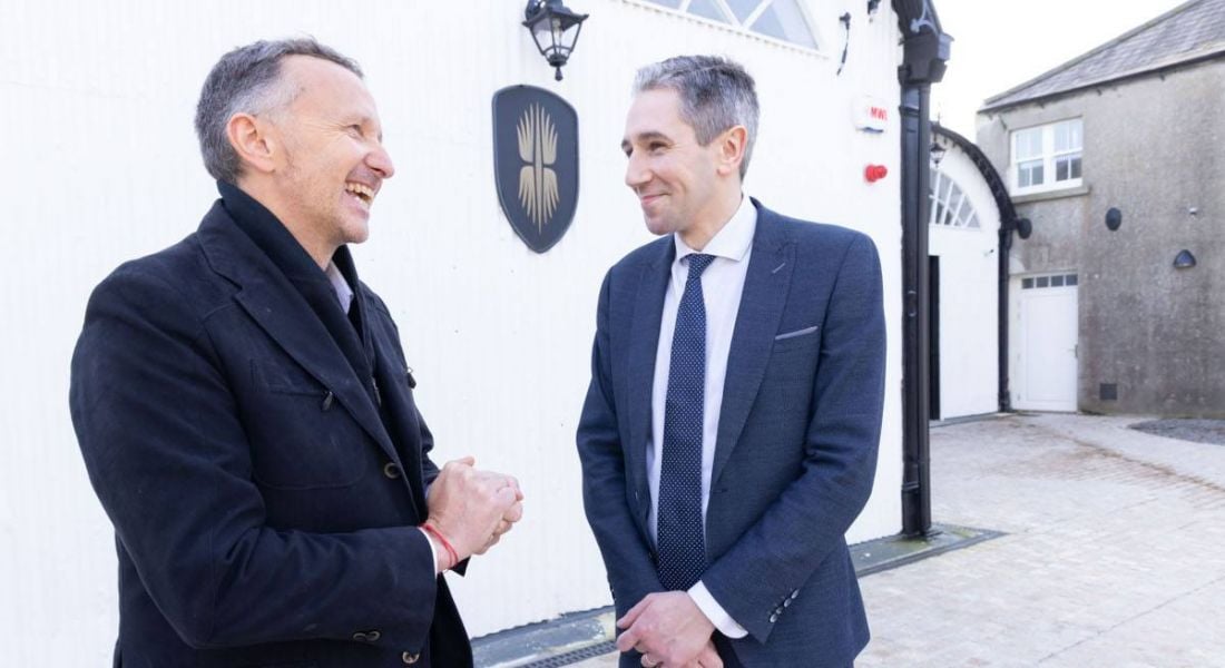 Two men standing outside a white building celebrating the announcement of jobs for Cool Planet.