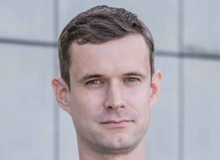 Photo of a man standing in front of a grey wall. He is doctor David McKeown of UCD.