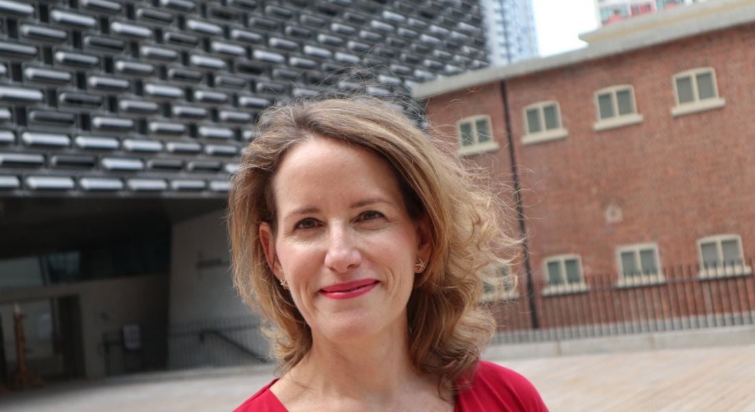 A woman standing outside a building and smiling. She is Diana Wu David.