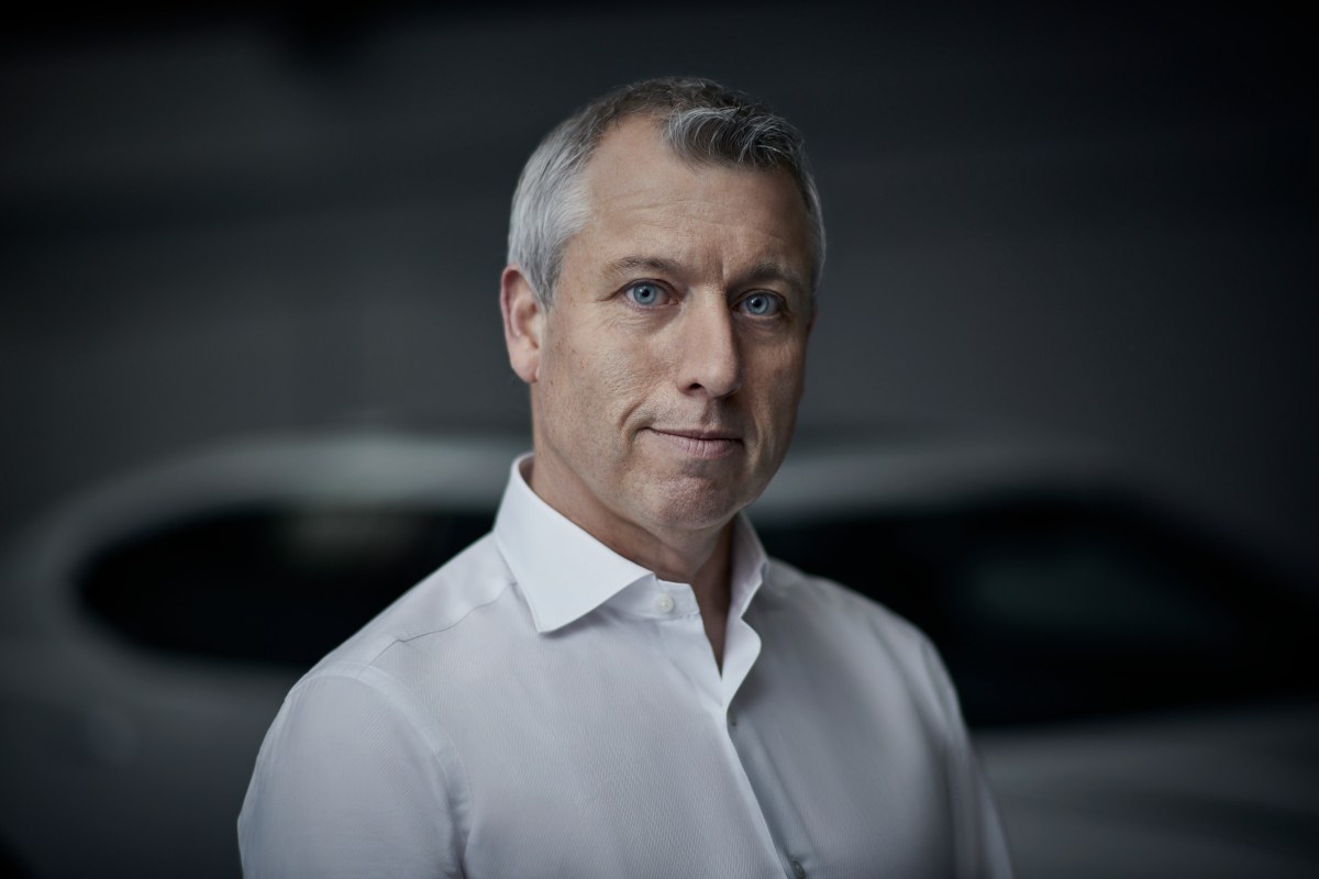 A man in a white shirt standing with a white car in the background. He is Paul Clifford of DCEV.