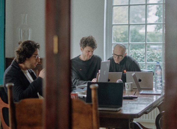 Three men seated around a table in an indoor space.