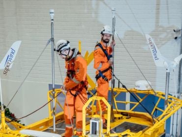 Two men in high visibility gear standing on top of a yellow buoy in a large room. They are technicians with the company Green Rebel.