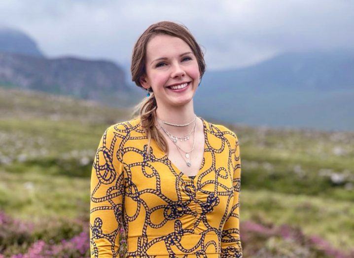 Catherine Williams, cybersecurity professional with BT standing with green grass and misty mountains in the background behind her.