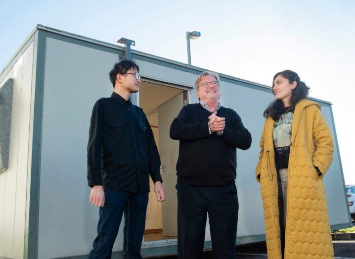 Two men and a woman standing in front of a small building, with a slightly overcast sky above them. They are part of the International Energy Research Centre at the Tyndall National Institute.