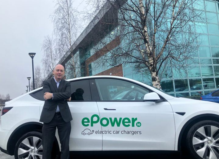 A man leans on a car behind him that has the ePower logo on it.