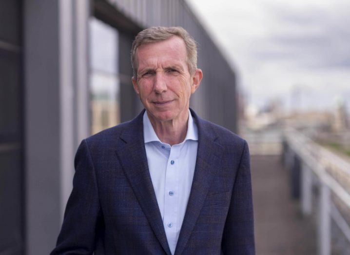 A man in a suit standing next to a building and a railing. He is Karl Flannery of Storm Technology.