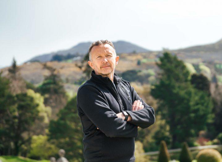 A man standing with his arms crossed, with trees and hills in the background. He is Norman Crowley of Cool Planet Group.