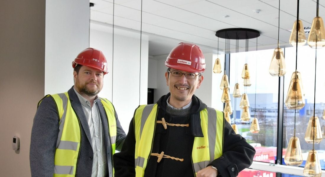 Two men wearing high-vis jackets and hardhats standing at a new Pentagon Technologies facility under construction.