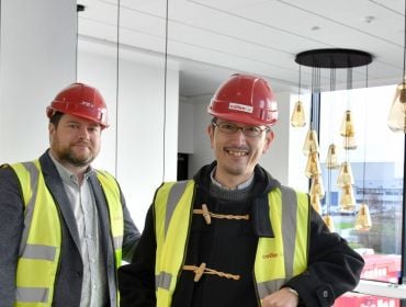 Two men wearing high-vis jackets and hardhats standing at a new Pentagon Technologies facility under construction.