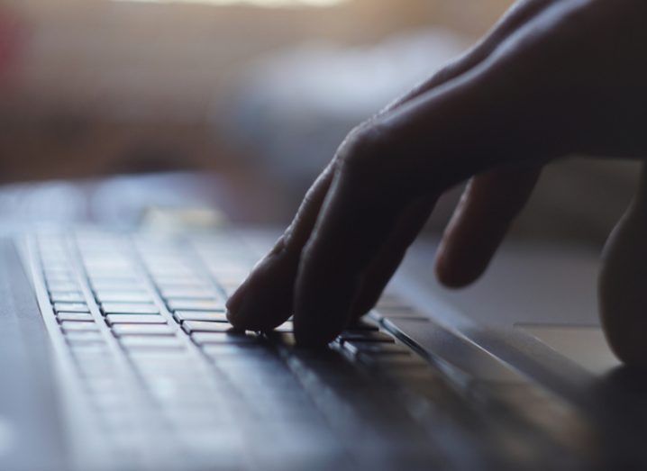 close-up of laptop keyboard with hand resting on it