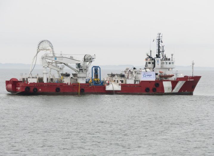 A large boat in the middle of the sea is laying fibre cables.