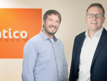 Two men standing together in front of a wall that has the Kentico logo on it. They are part of Kentico and Granite Digital.