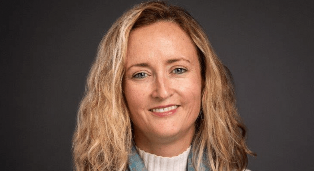 A woman with blonde hair smiles in front of a dark grey background. She is Sinéad Bailey, country lead for Ireland at Bristol Myers Squibb.